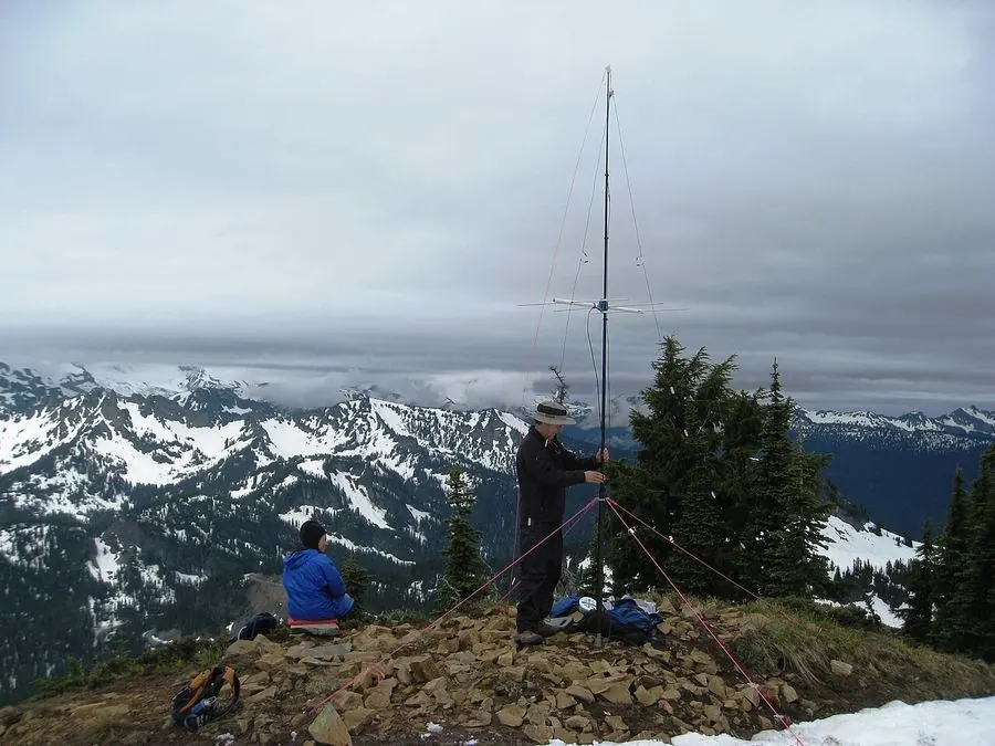 Operators raising a mast with a Yagi antenna on a mountain summit
